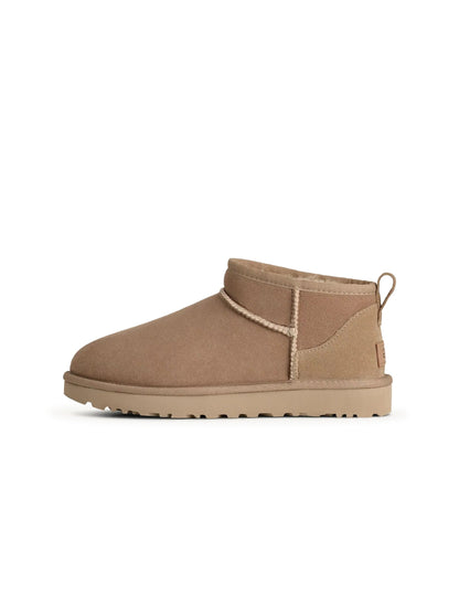 UGG Women's Classic Ultra Mini Sand sneakers showing beige suede uppers and soft sole, casual women's footwear by Denim Exchange.