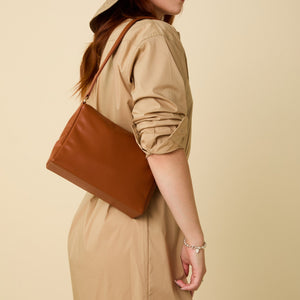 Allégorie Gala shoulder bag in brown leather, featuring a sleek design with a top handle and adjustable strap.