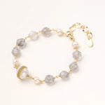 Bracelet with cloudy quartz beads, freshwater pearls, and gold-wrapped baroque pearl centerpiece on white background.