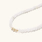 Three layered white beaded bracelets with carved orange agate lotus centerpiece and freshwater pearls on cream background.
