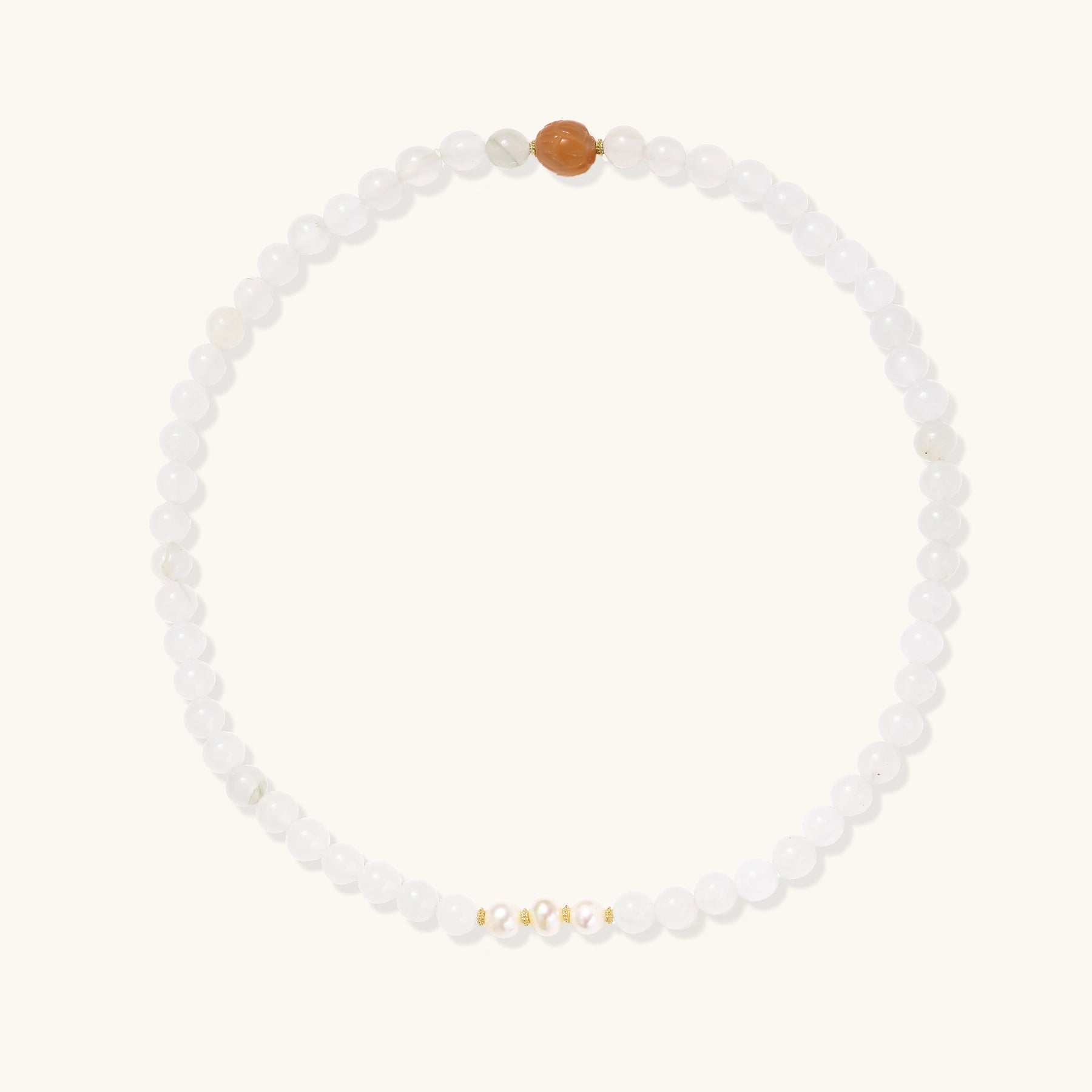 Three layered white beaded bracelets with carved orange agate lotus centerpiece and freshwater pearls on cream background.