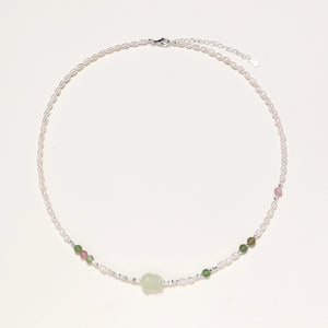 Delicate pearl necklace with pale green serpentine jade centerpiece and colorful agate beads on cream background