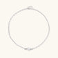 Dainty rhodium-plated silver chain necklace with centered 10mm freshwater pearl and crystal accents on cream background