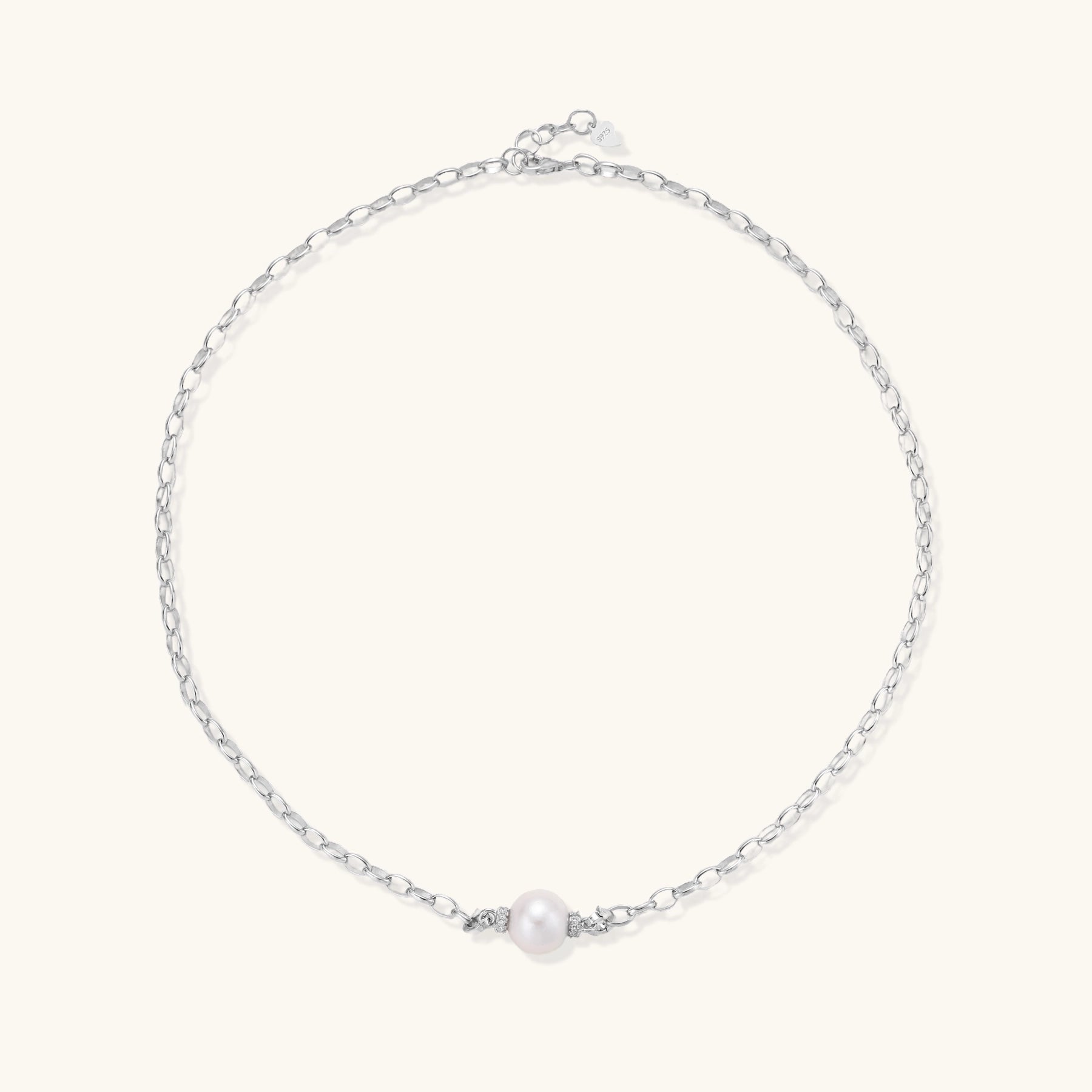 Dainty rhodium-plated silver chain necklace with centered 10mm freshwater pearl and crystal accents on cream background