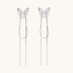 Pair of silver threader earrings with crystal butterfly tops and long chain drops on cream background.