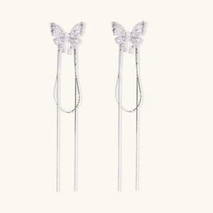 Pair of silver threader earrings with crystal butterfly tops and long chain drops on cream background.