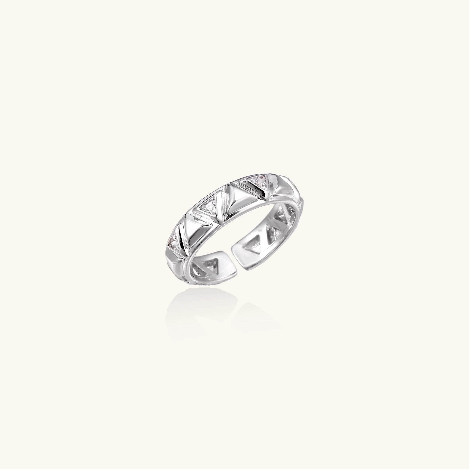 White gold adjustable ring with geometric triangle cutouts and zirconia stones on cream background