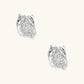 Close-up of sculptural hoop earrings with lattice center band and smooth twisted edges in white gold-plated brass with zirconia