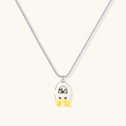 Chrome egg-shaped pendant with kawaii face, yellow bow, and pearl detail on silver chain against white background