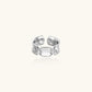 Adjustable silver-toned ring with sculptural stitch design across polished white gold-plated brass band