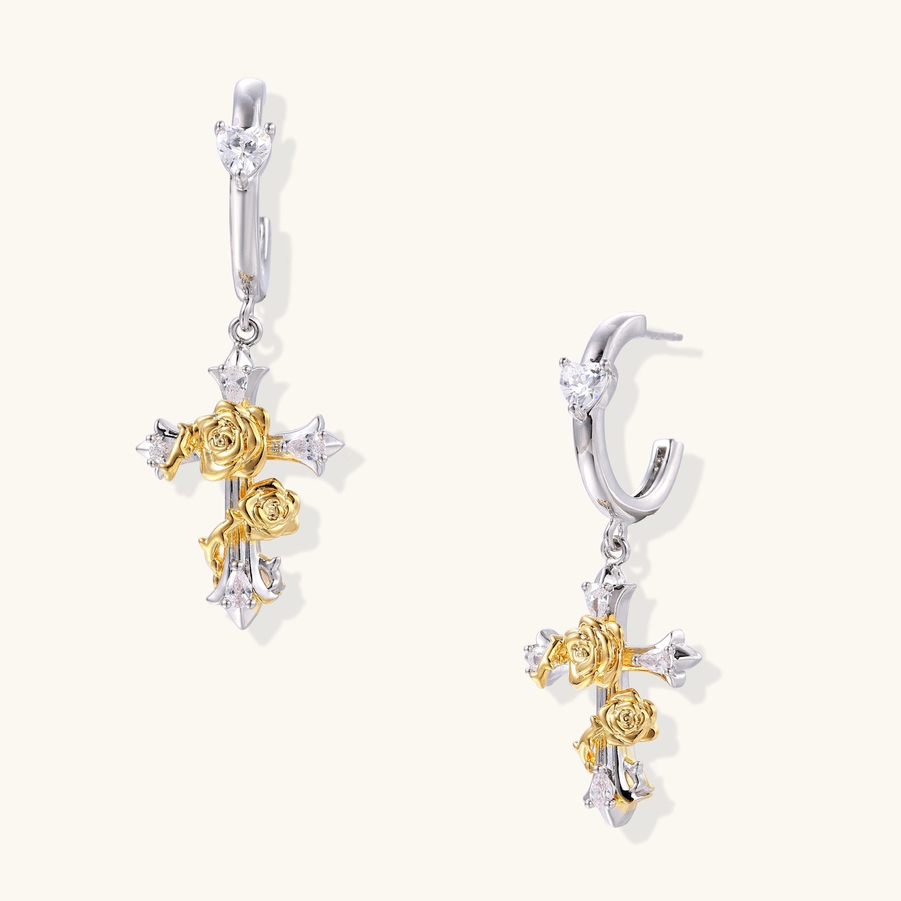 Two-tone huggie hoops with gold rose crosses and star zirconia accents on cream background