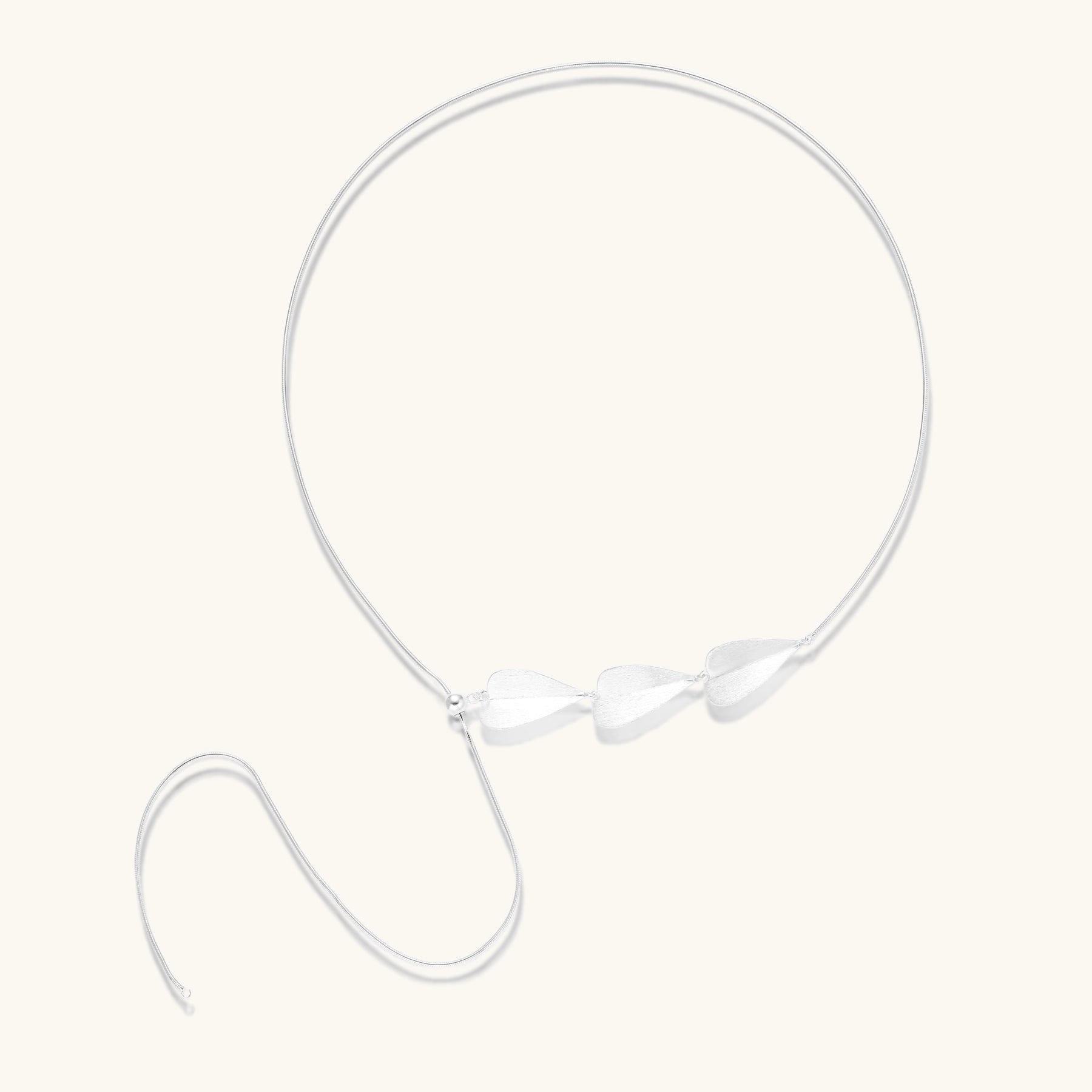 Minimalist sterling silver necklace with three brushed leaf-shaped pendants on delicate chain against white background