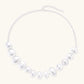 Graduated pearl-finish silver discs forming an organic bubble bib necklace on delicate chain against cream background.