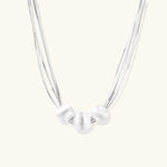 Sterling silver multi-strand necklace with three brushed round beads on cream background