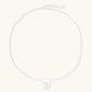 Minimalist brushed sterling silver dome pendant on delicate chain against cream background, showing matte textured finish