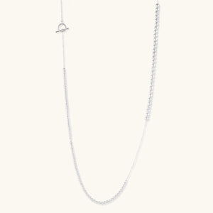 Long sterling silver beaded necklace with graduated sphere design, toggle clasp, and delicate chain extension on white background