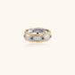 Two-tone ring with brushed silver center, gold beaded edges, and blue zirconia stones on white background.