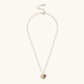 Gold-plated necklace with pink and purple enamel flower pendant featuring crystal accents on cream background