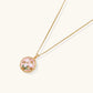 Gold pendant with pink enamel backdrop, white freshwater pearls as tulip blooms, and green leaf accents on rope chain.