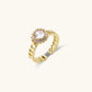 Gold-plated adjustable ring with twisted chain band, central cubic zirconia stone surrounded by crystal halo on cream background