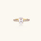 Gold-plated solitaire ring with oval zirconia center stone and pavé band on cream background