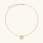 Delicate gold-plated necklace with three interlocking circle rings forming a minimalist knot pendant on cream background