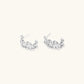 White gold plated sculptural hoop earrings with organic wavy edges and reflective metallic finish on cream background