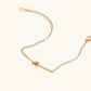 Delicate gold chain bracelet with minimalist bar and centered knot detail on cream background