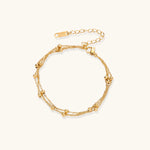 Three-strand gold-plated bracelet with clustered ball beads and adjustable clasp on cream background