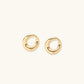 Pair of polished 18K gold-plated stainless steel teardrop earrings with hollow centers on cream background