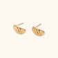 Chunky gold twisted rope huggie hoops with diagonal grooves and high-polish finish on cream background