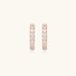 Gold pavé hoop earrings with two freshwater pearls nestled inside the curved design, featuring crystal-studded outer edge.