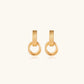 Gold stud earrings with vertical ridged bar connecting to triple interlocking circular rings on white background
