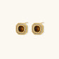 Gold-plated octagonal stud earrings with brown tiger's eye centers and cubic zirconia border on cream background.