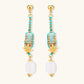 Gold-plated dangle earrings with turquoise threading, star charms, and white pearl beads against cream background.