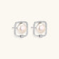 Rhodium-plated silver stud earrings with cushion frame, centered freshwater pearl, and tiny crystal accent