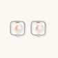 Rhodium-plated silver stud earrings with cushion frame, centered freshwater pearl, and tiny crystal accent