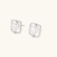 Rhodium-plated silver stud earrings with cushion frame, centered freshwater pearl, and tiny crystal accent