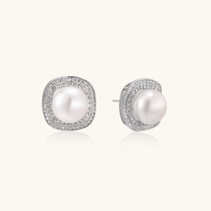 Rhodium-plated sterling silver stud earrings with round freshwater pearls surrounded by geometric crystal halos on cream background.