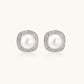 Rhodium-plated sterling silver stud earrings with round freshwater pearls surrounded by geometric crystal halos on cream background.