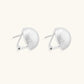 Brushed sterling silver half-dome clip-on earrings with textured surface against cream background