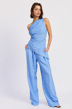 Emory Park Elsie asymmetrical top in soft fabric with unique hemline, styled with neutral accessories and a casual backdrop.