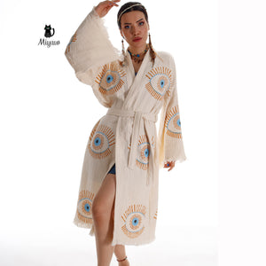 Blue evil eye inspired boho chic caftan by Miyawfashion, flowing fabric with intricate patterns and vibrant colors.