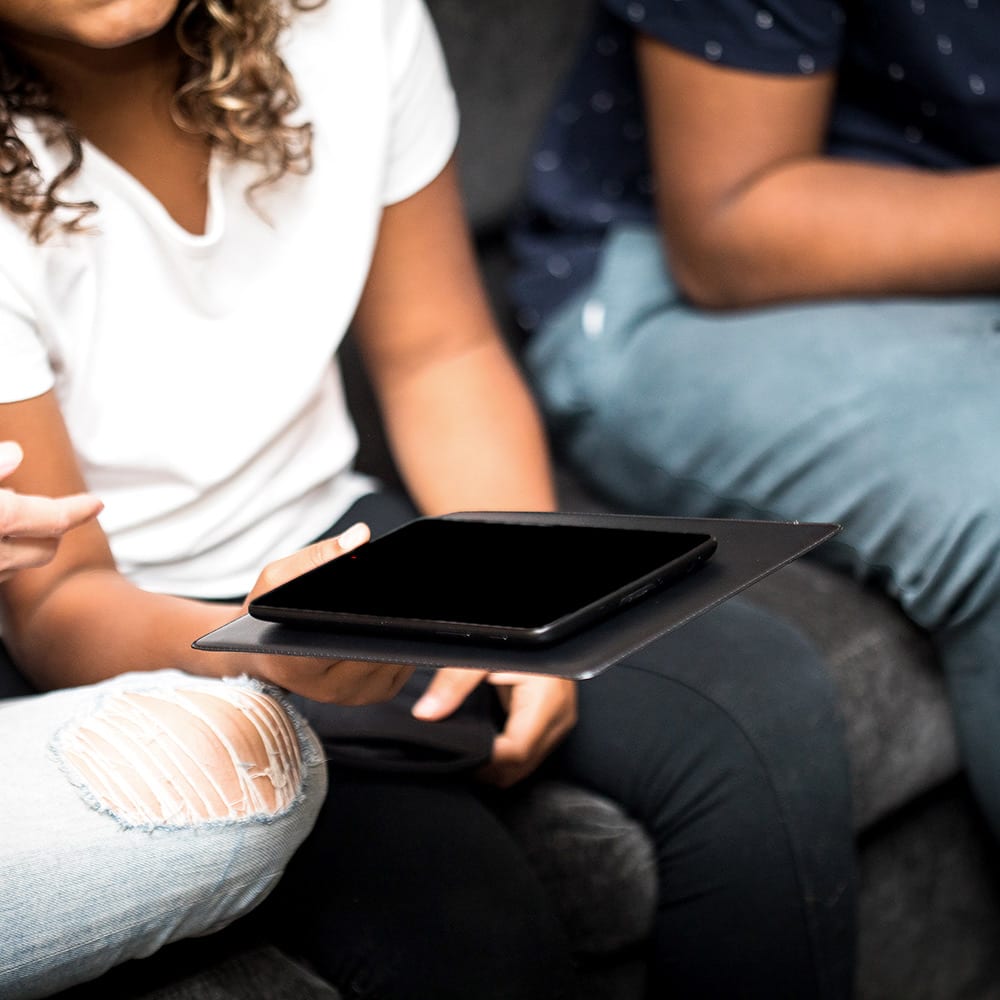 Shield Your Body SYB Tablet Pad shown on a couch beside multiple tablets