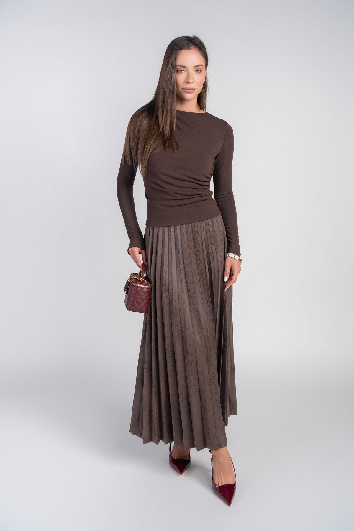Brown pebble leather pleated maxi skirt by Adina Las Vegas, featuring a flowing design and detailed pleats.
