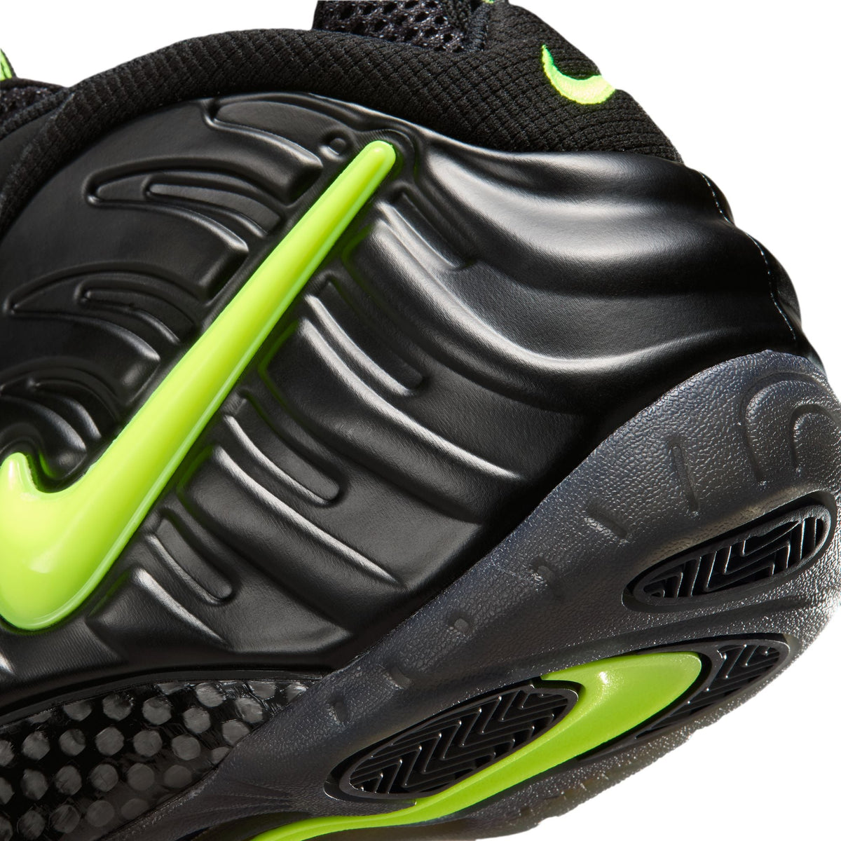 Nike men's Air Foamposite Pro sneakers in black and Voltage with sleek design and textured upper, shown from side angle.