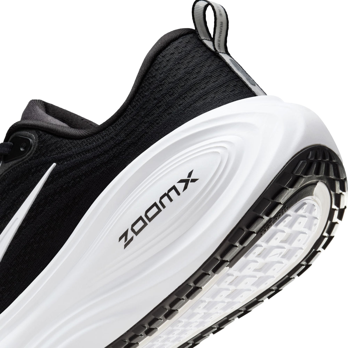 Black and white Nike men's Vomero Plus sneakers viewed from the side, showing layered mesh and cushioned sole