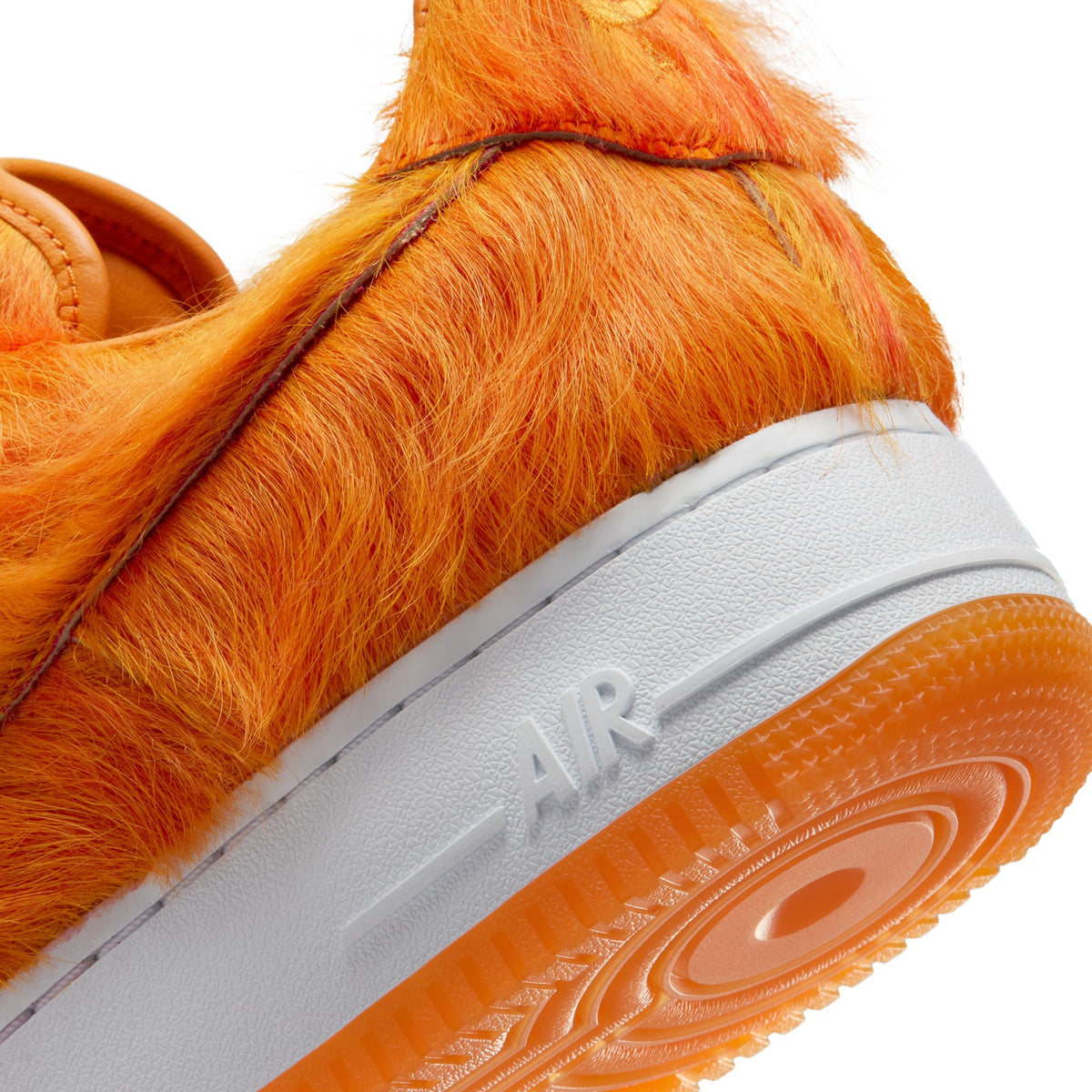 Nike men's Air Force 1 sneakers in orange pony hair, featuring a classic low-top design and white sole.