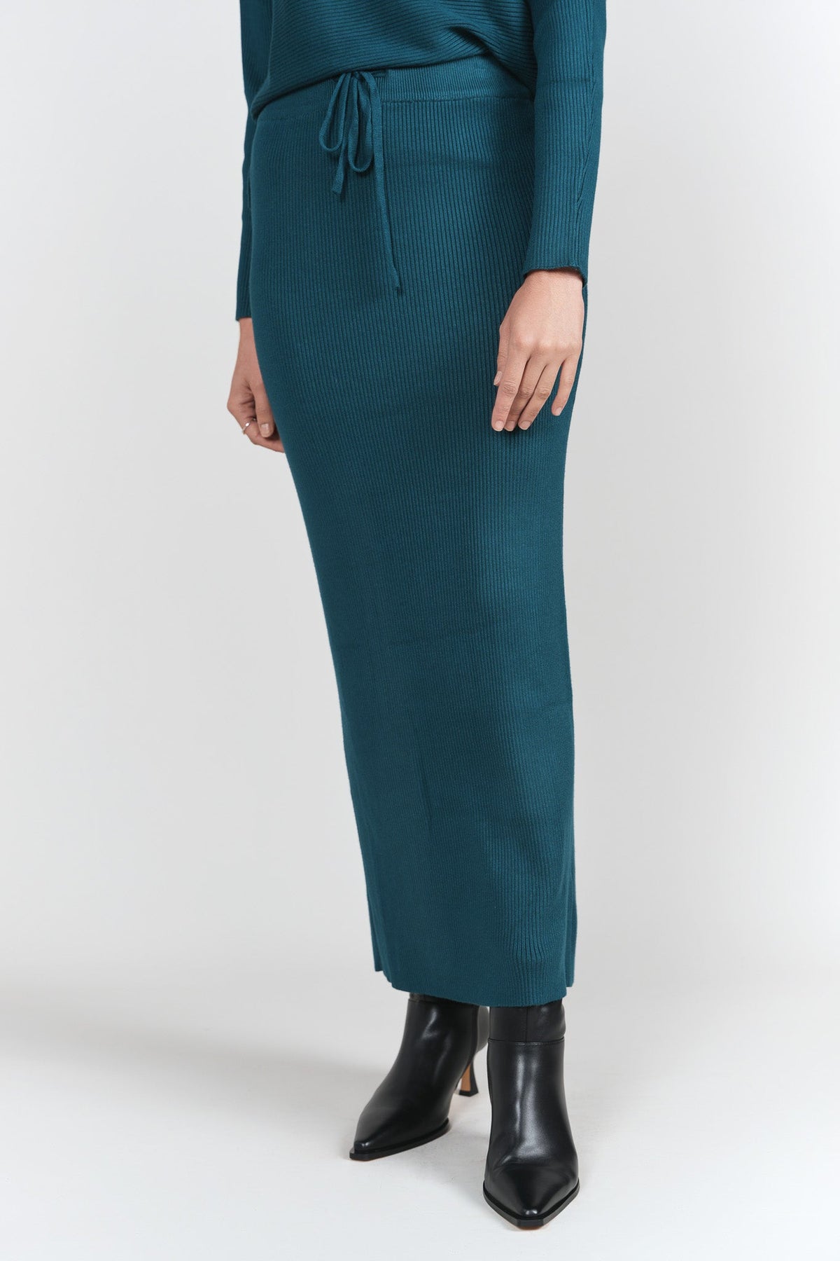 Teal ribbed sweater skirt by Adina Las Vegas, stylish and fitted, shown on a model with a casual winter outfit.