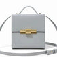 Thebagicon Nina cigar box bag in black leather with gold-tone hardware, featuring a structured rectangular shape and top handle.